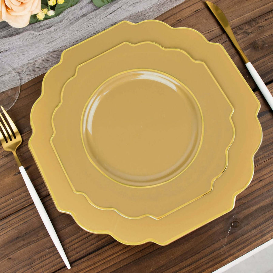 Gold scalloped dinner plates set on a wooden table with cutlery.