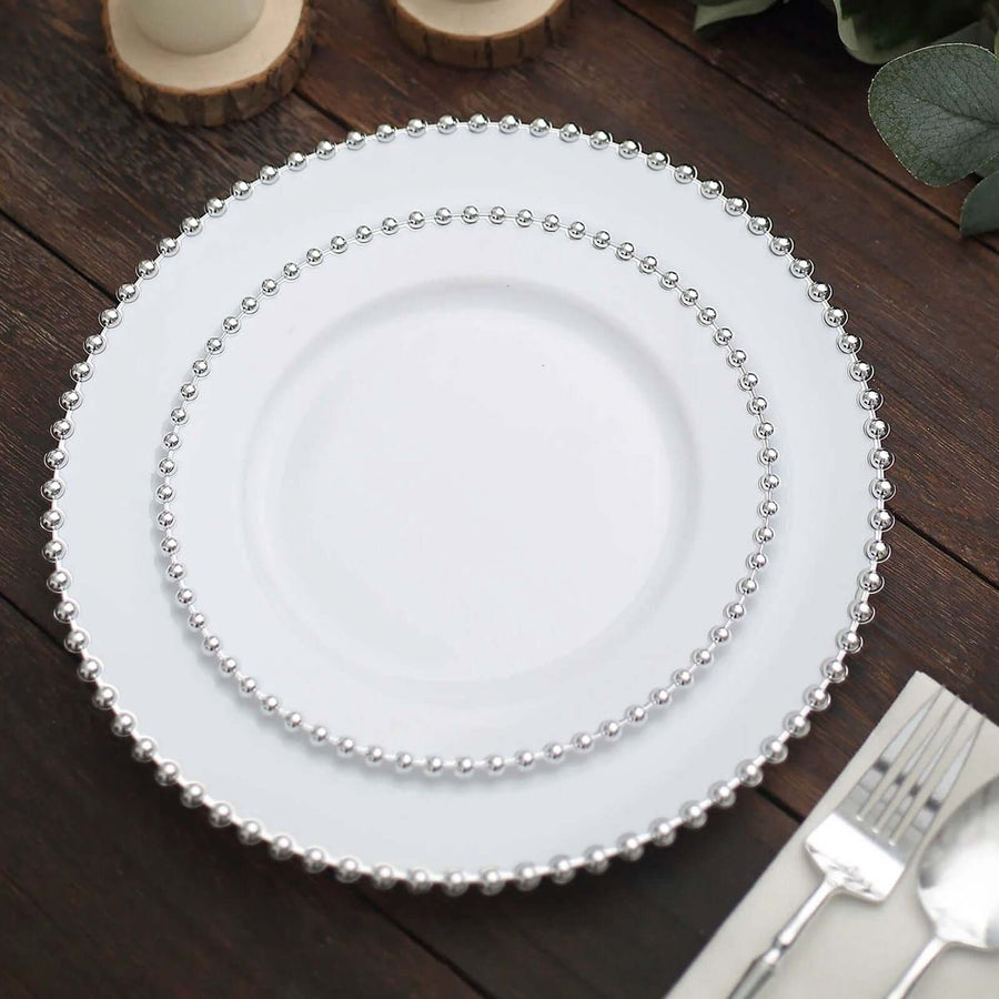 Elegant white plates with silver beaded rim on a wooden table setting.