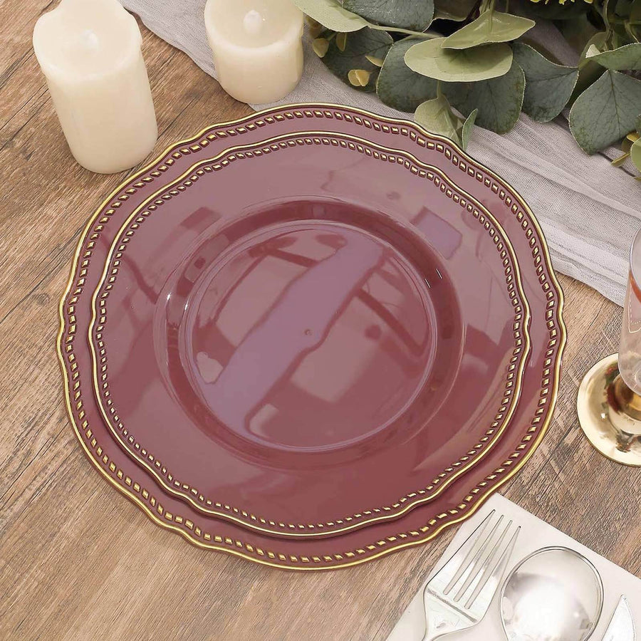 Elegant burgundy plate with gold trim on a rustic wooden table setting.