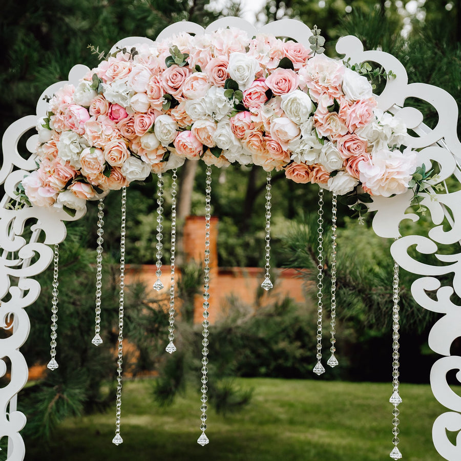 Floral wedding arch with pink and white roses and hanging crystals.