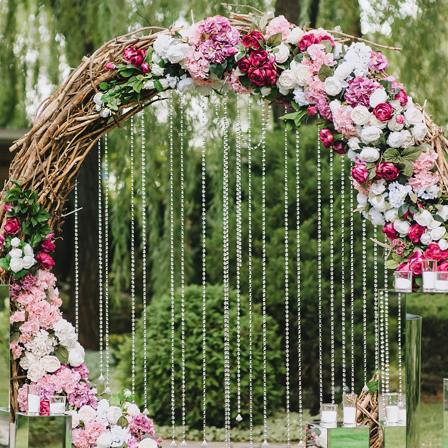 Floral wedding arch with pink and white flowers, cascading beads, and greenery.