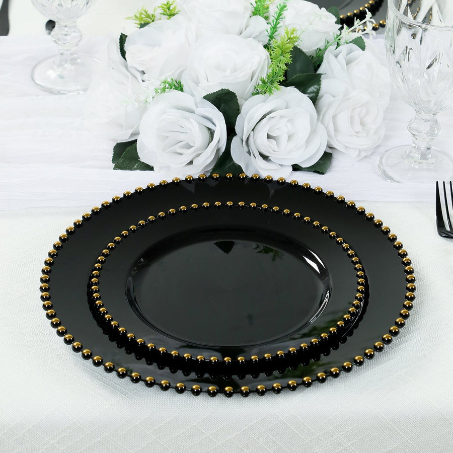Black dinner plates adorned with gold beads, elegantly set with white roses.