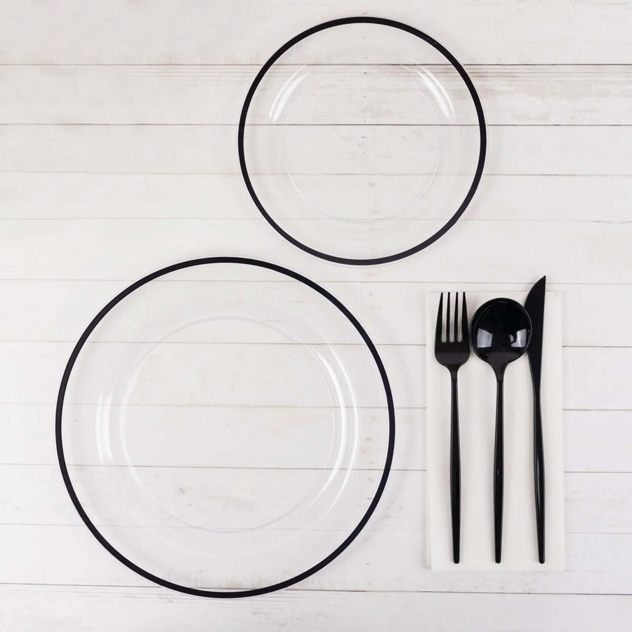 Transparent plates with black rim and cutlery on a white background.