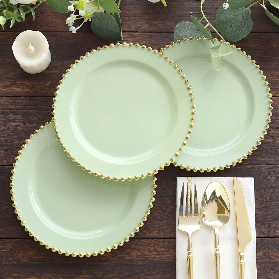 Green plates with gold beaded edges on a wooden surface.