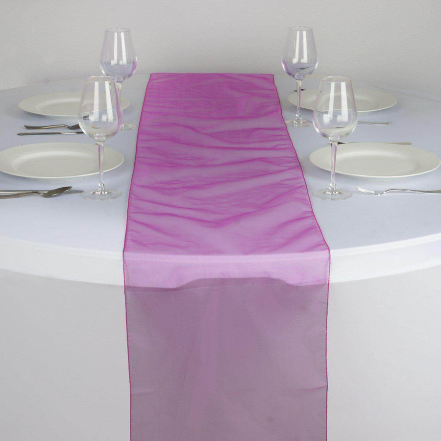 Purple organza table runner on a dining table set with plates and glasses. #whtbkgd