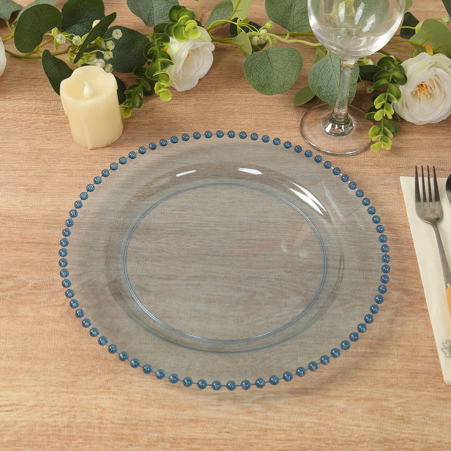 Clear glass plate with blue bead trim on a wooden table setting.