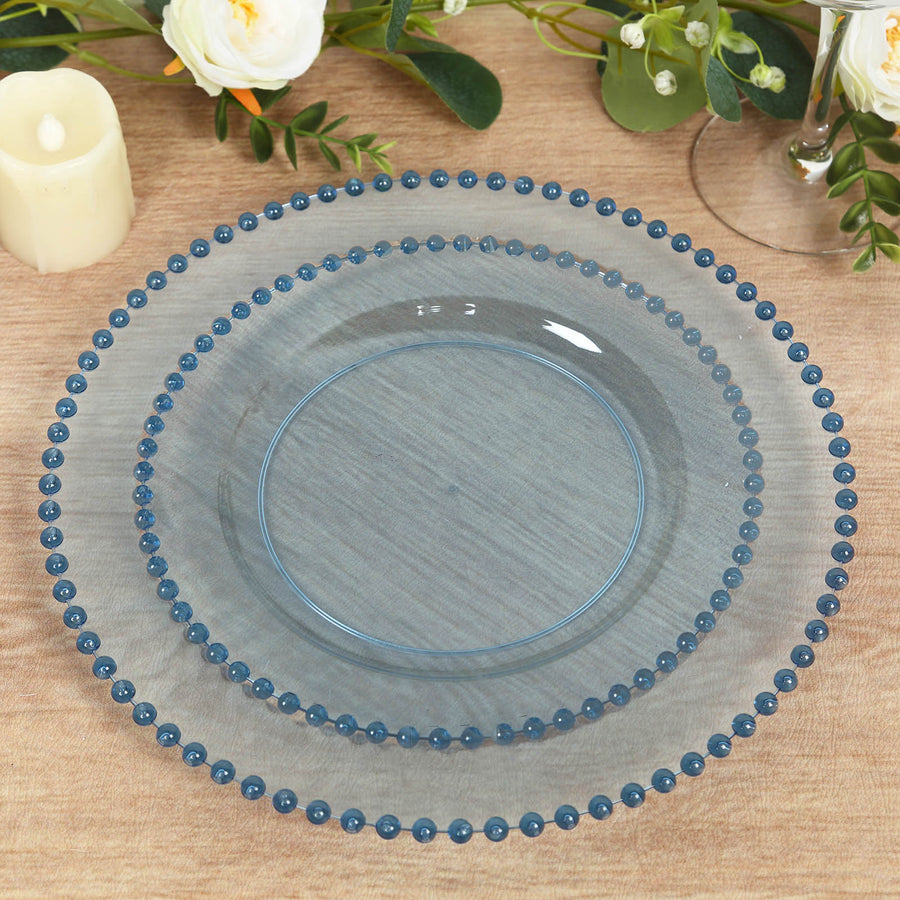 Blue beaded glass plates stacked on a wooden table.