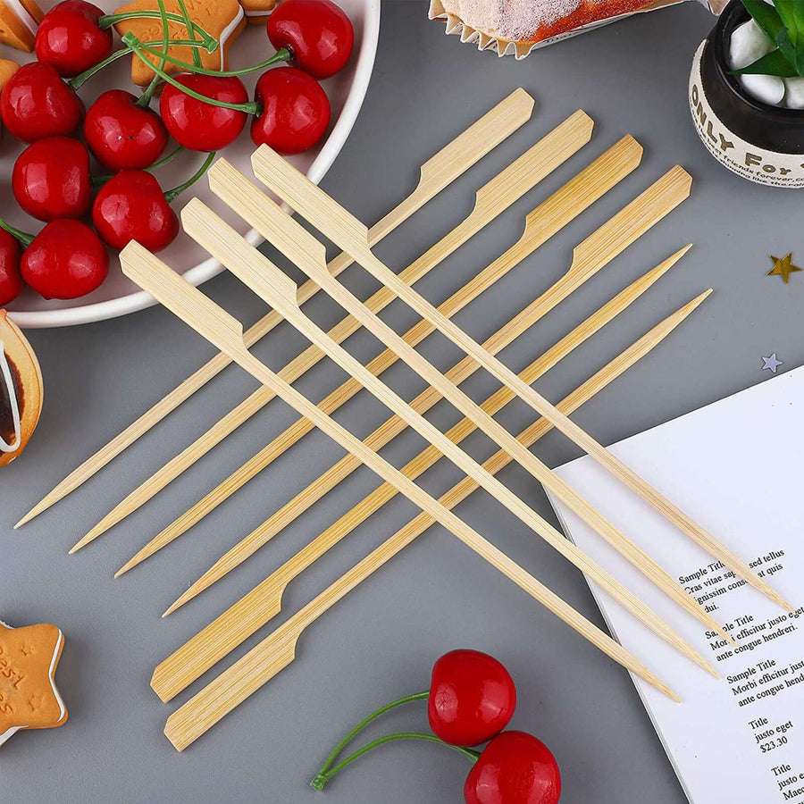 Bamboo skewers arranged on a table with cherries and baked goods.