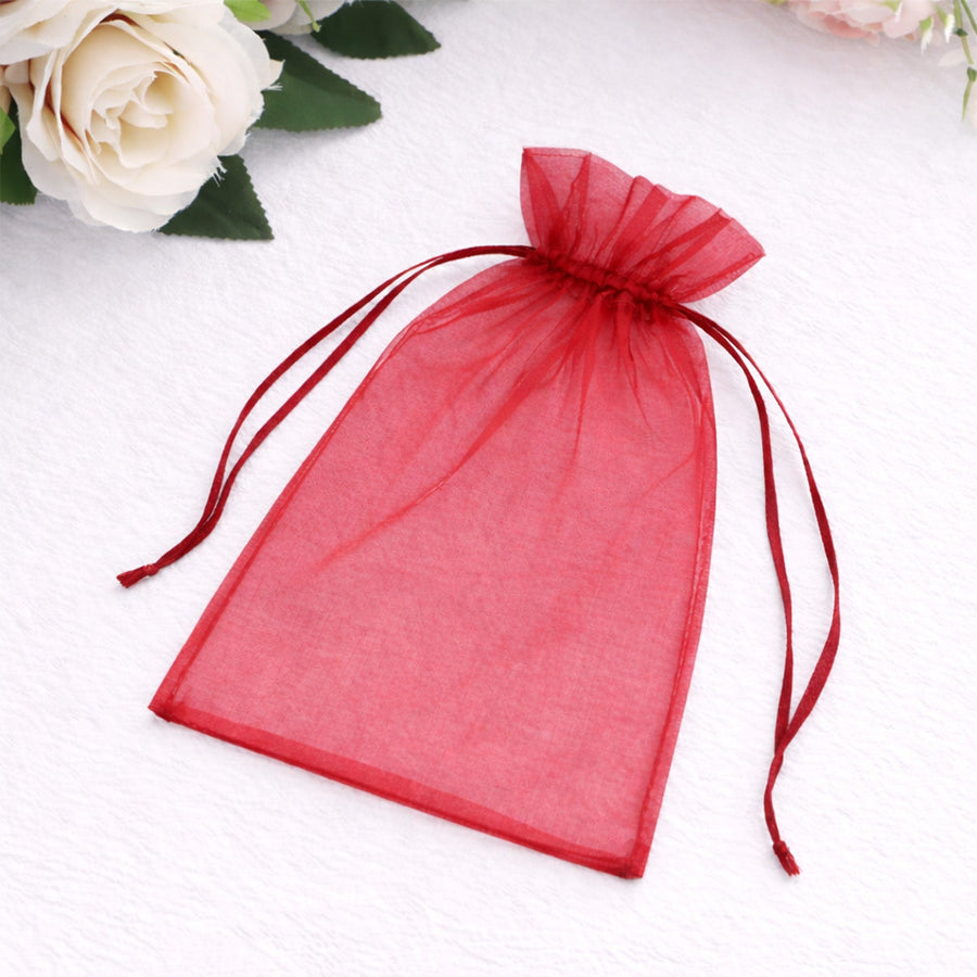 Red organza gift bag with drawstring closure on a soft white background.