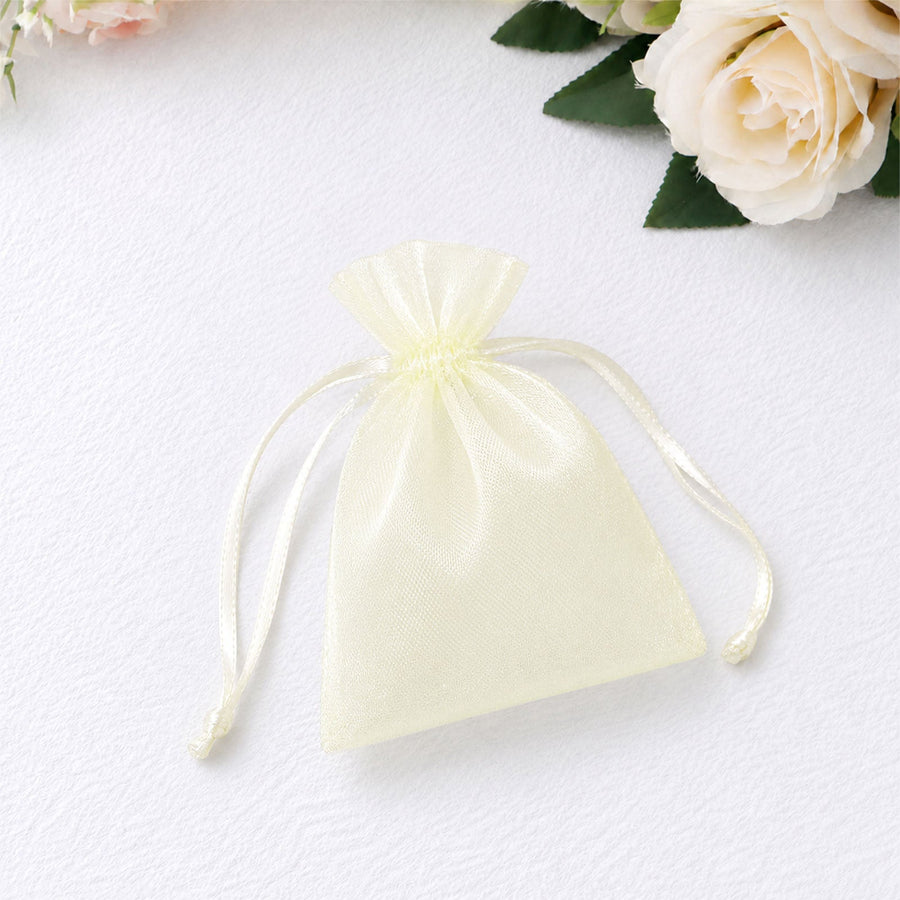 Cream organza drawstring gift pouch with white roses on a textured background