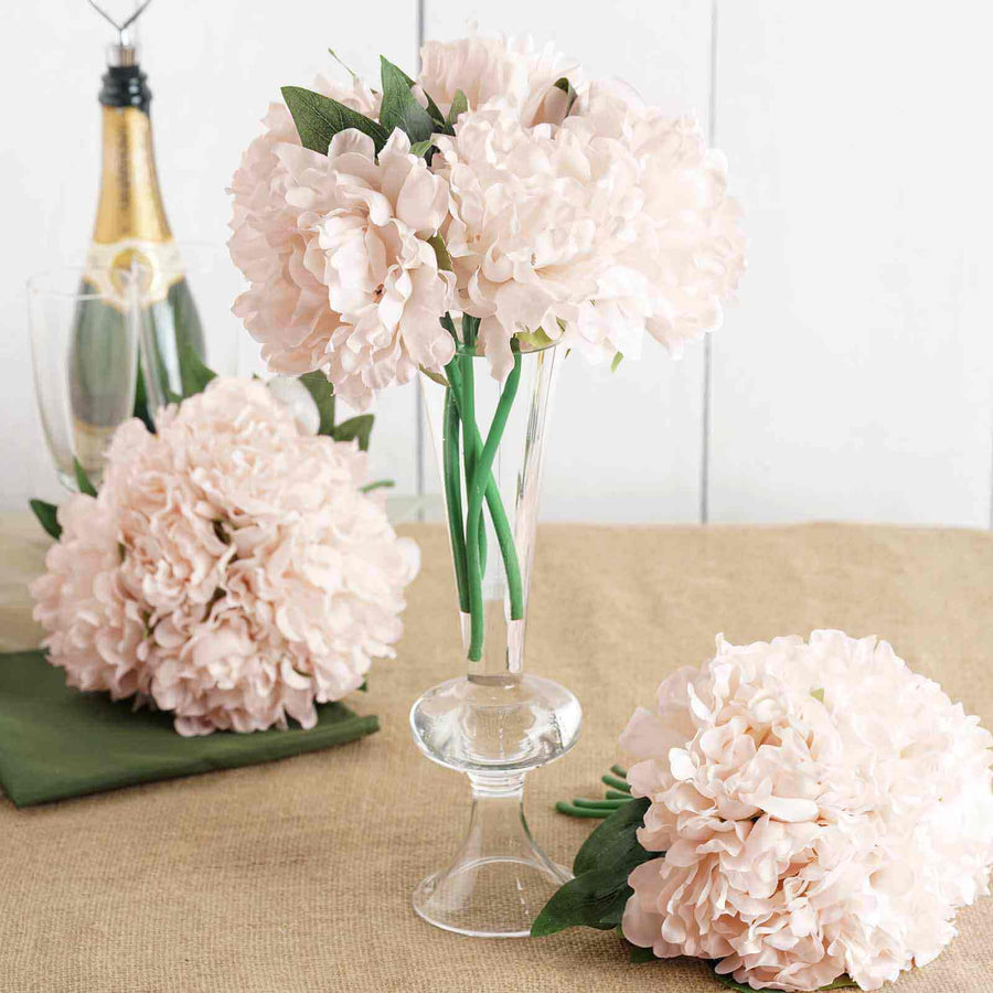 Pink peony flowers in a glass vase on a table.