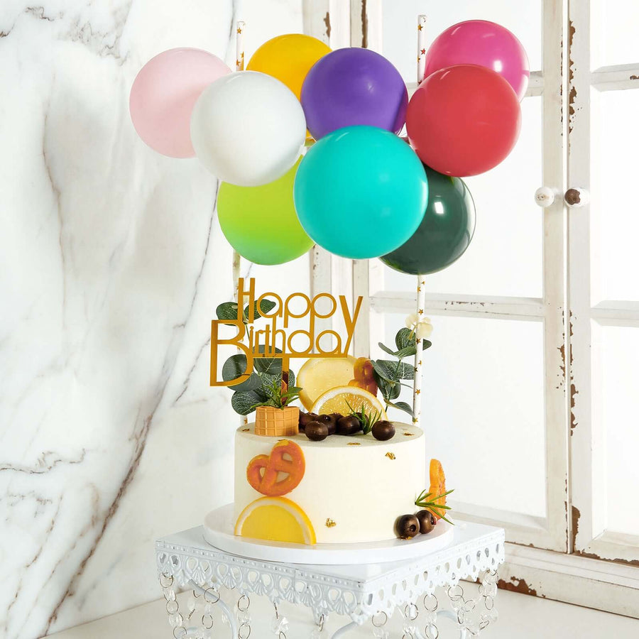 Birthday cake decorated with colorful balloons and fruits.