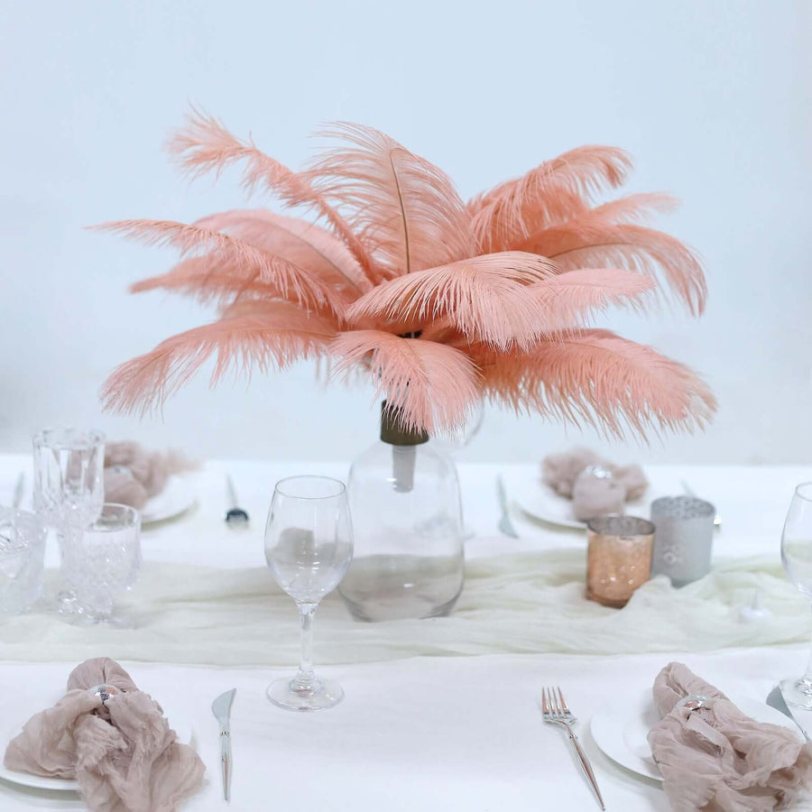 Pink feather centerpiece in a glass vase on a dining table.