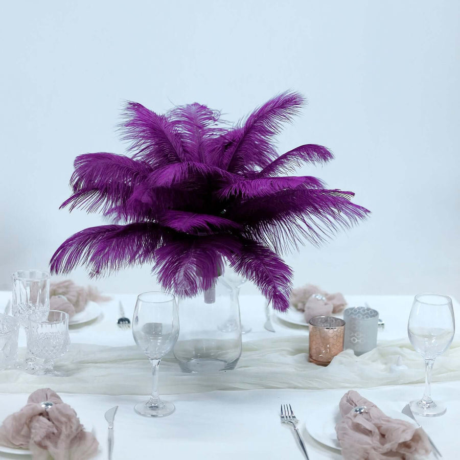Purple feather centerpiece in a clear vase on a dining table.
