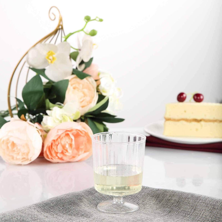 Clear plastic cup with white beverage and decorative flowers in background.