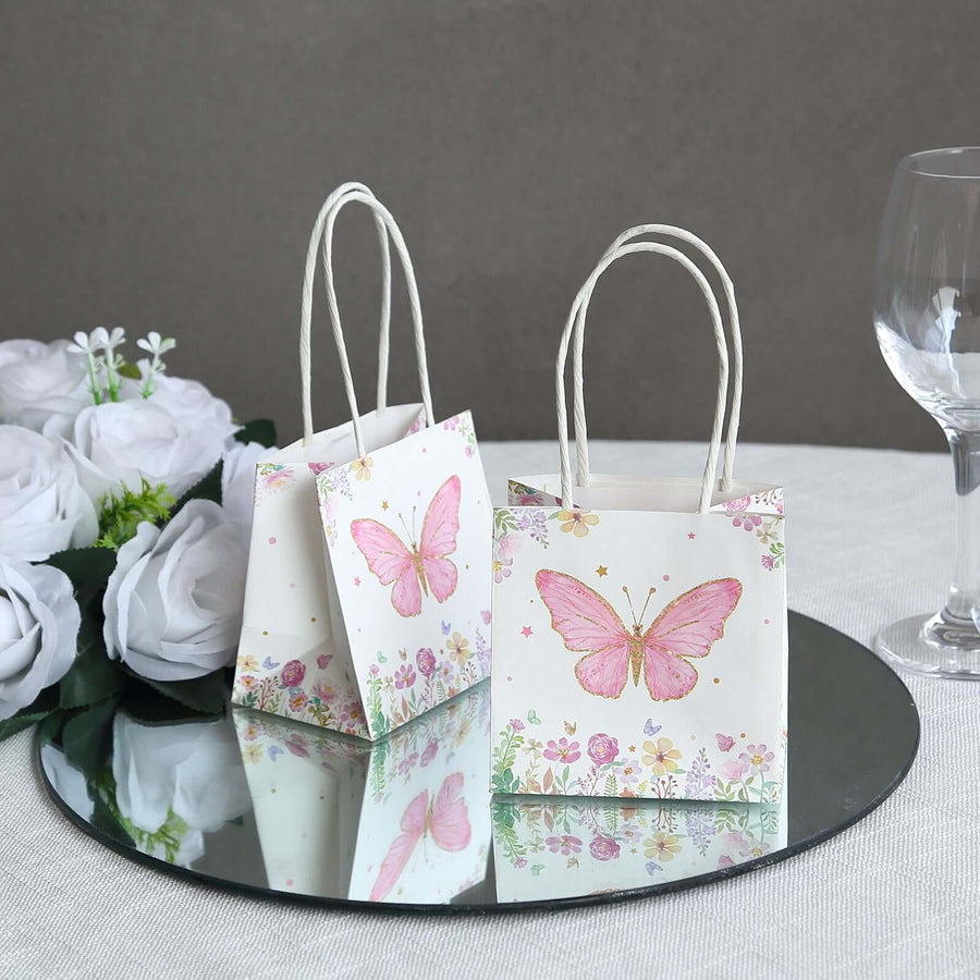 Butterfly print gift bags on a mirrored surface with flowers and glassware.
