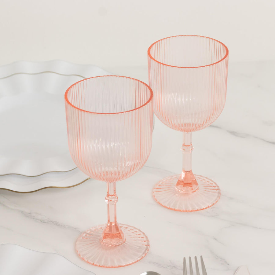 Pink ribbed glassware set on a marble surface with elegant plates.