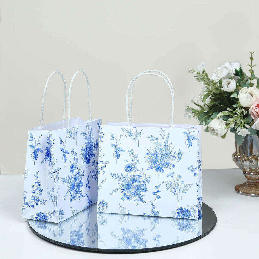 Floral gift bags with handles on a mirrored surface.