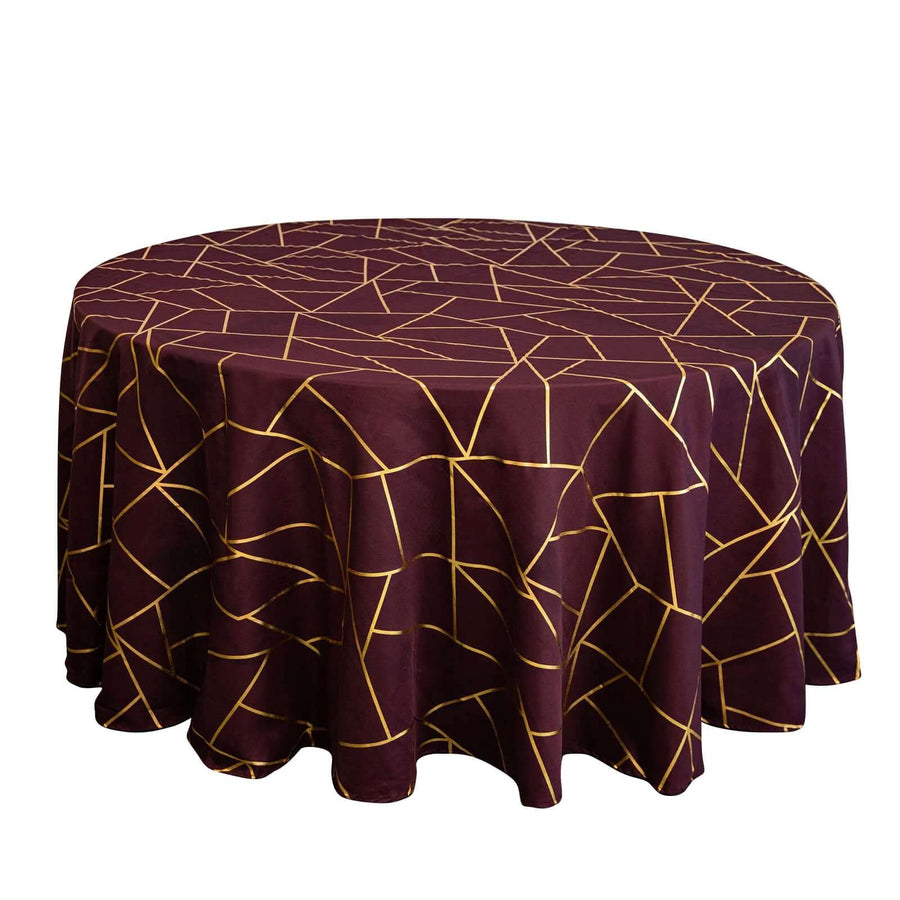 Round burgundy tablecloth with gold geometric pattern on a white background.