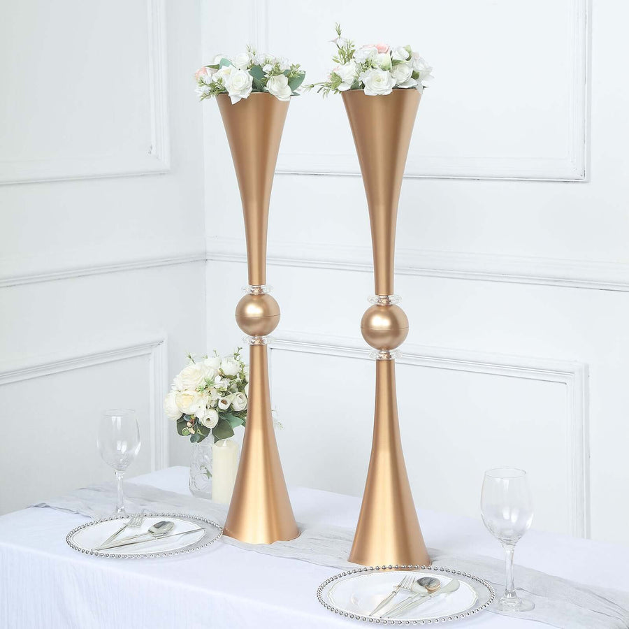 Elegant gold flower vases with floral arrangements on a dining table.