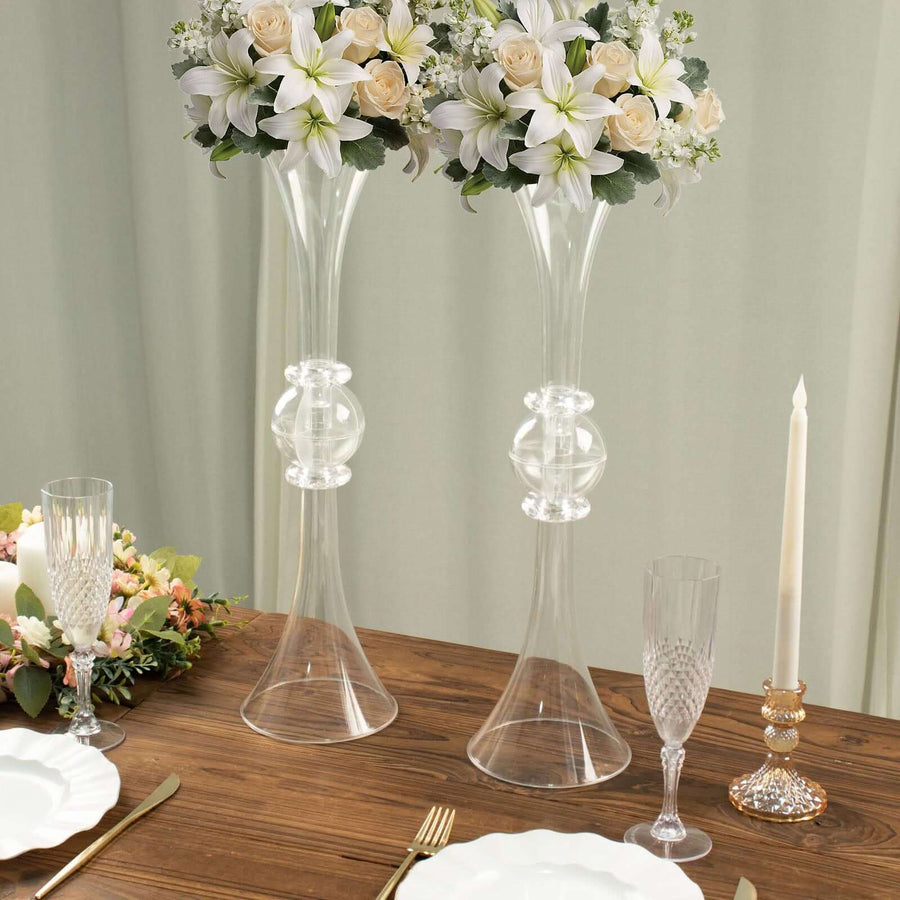 Elegant glass vases with floral arrangements on a wooden dining table.