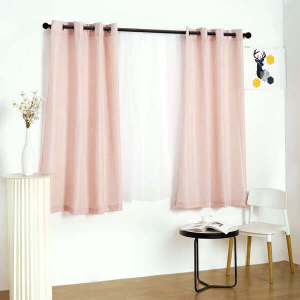 Sheer pink curtains hanging on a black rod in a stylish room setting.