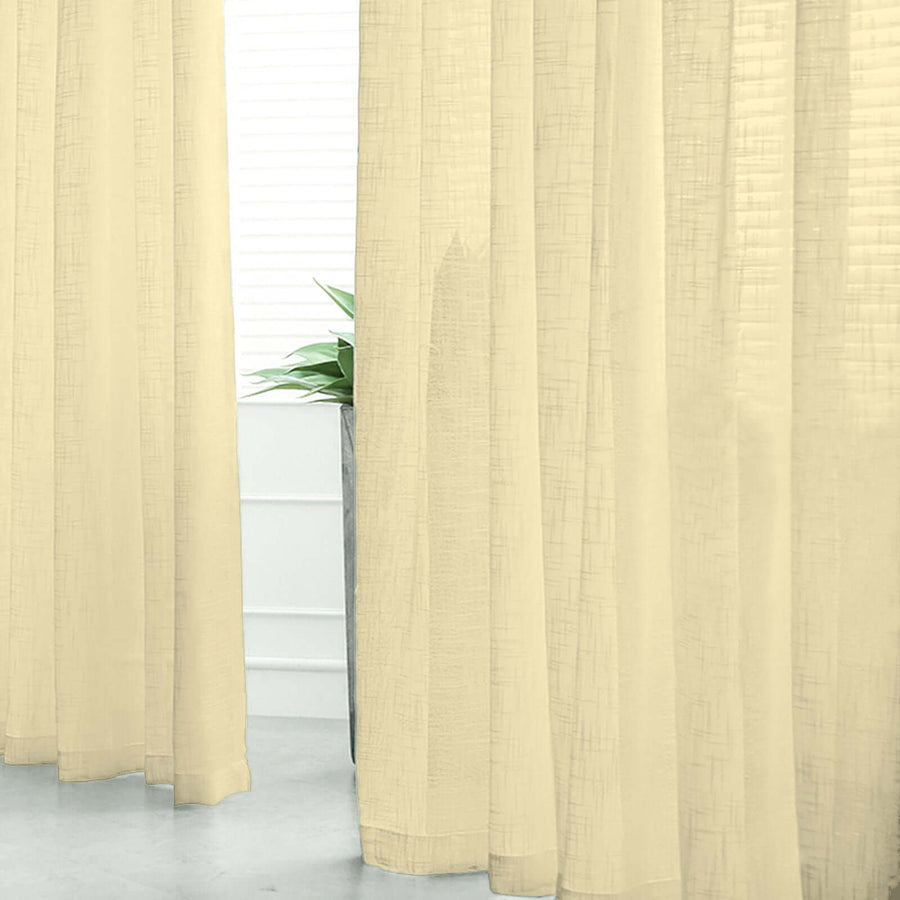 Sheer beige curtains softly draping in a bright room with indoor plants.