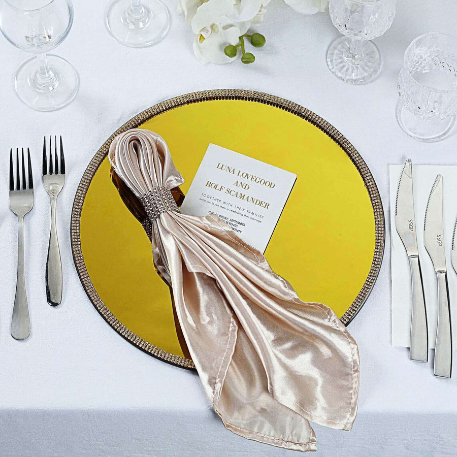 Elegant gold charger plate with silk napkin and wedding invitation on a table setting.