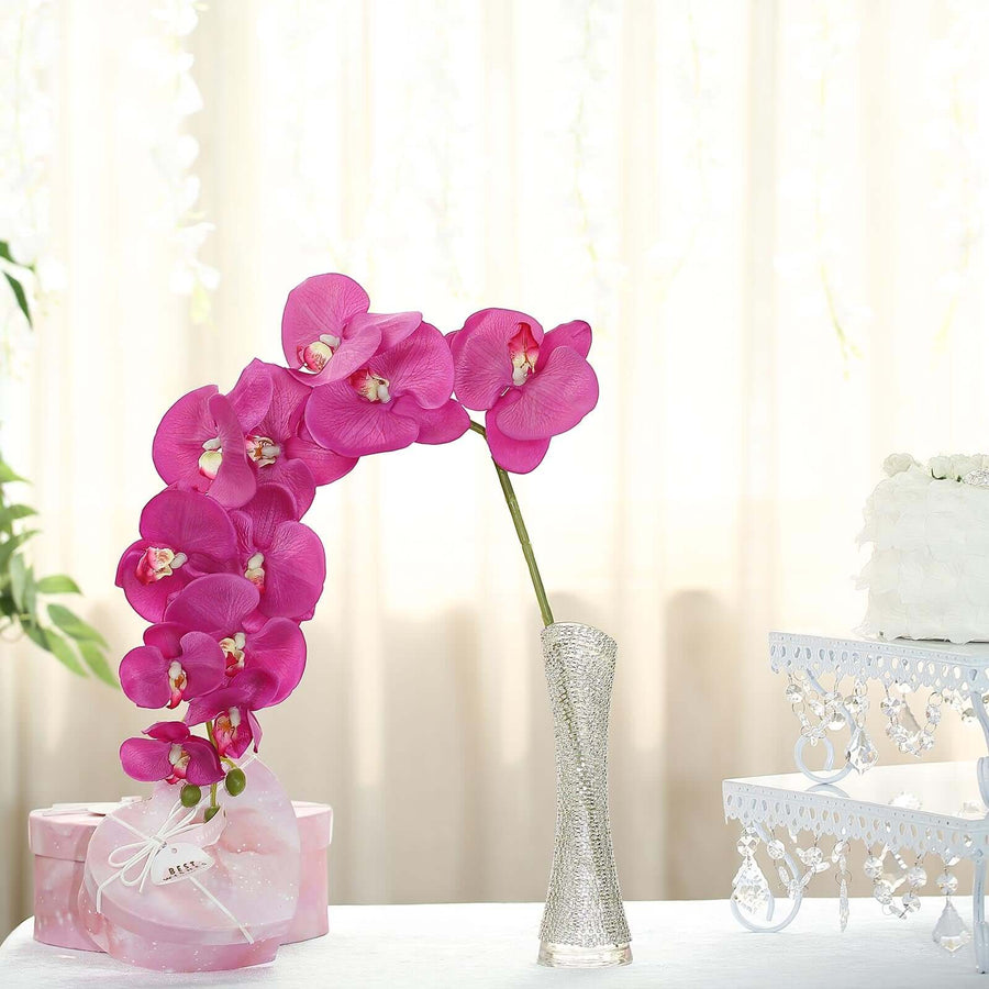 Pink orchid arrangement in a decorative vase on a soft background.