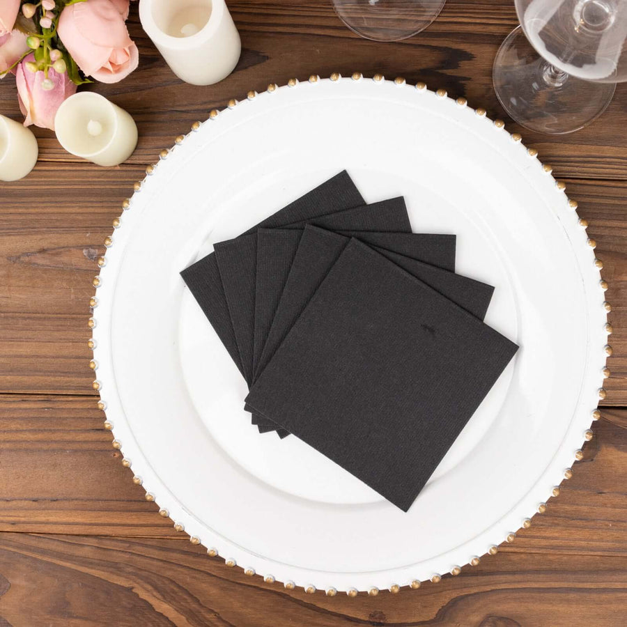 Black square coasters on an elegant white plate with floral accents.
