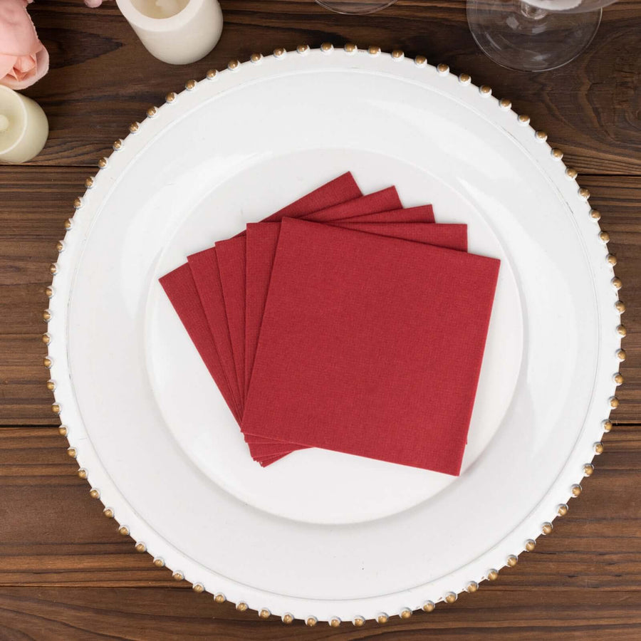 Red fabric napkins stacked on a decorative plate.
