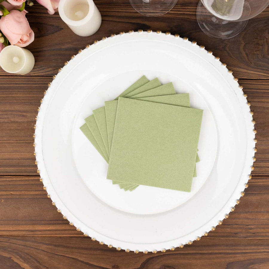 Green paper napkins stacked on a decorative white plate.