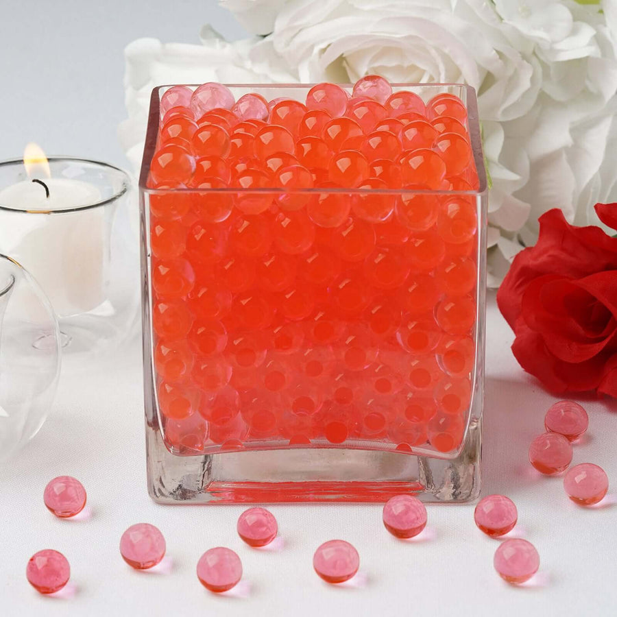 Glass vase filled with vibrant orange water beads.