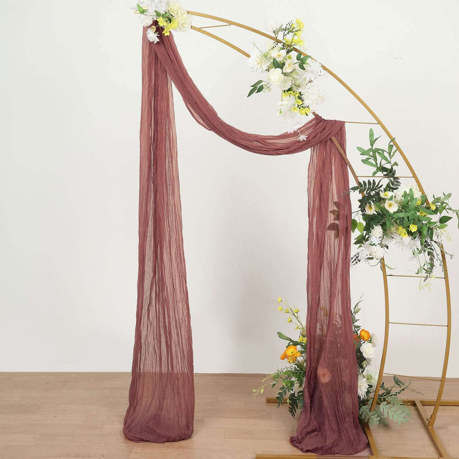 Burgundy sheer fabric draped on a gold arch with floral accents
