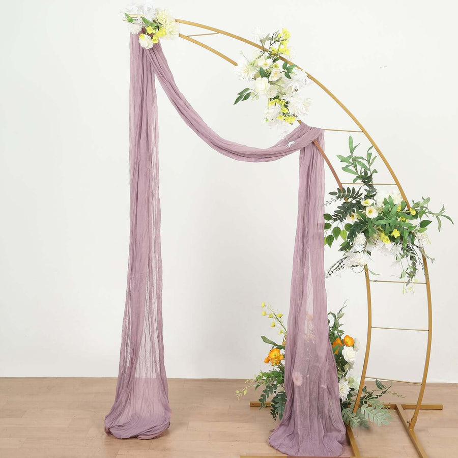 Purple draped fabric on a gold arch with flowers for decor