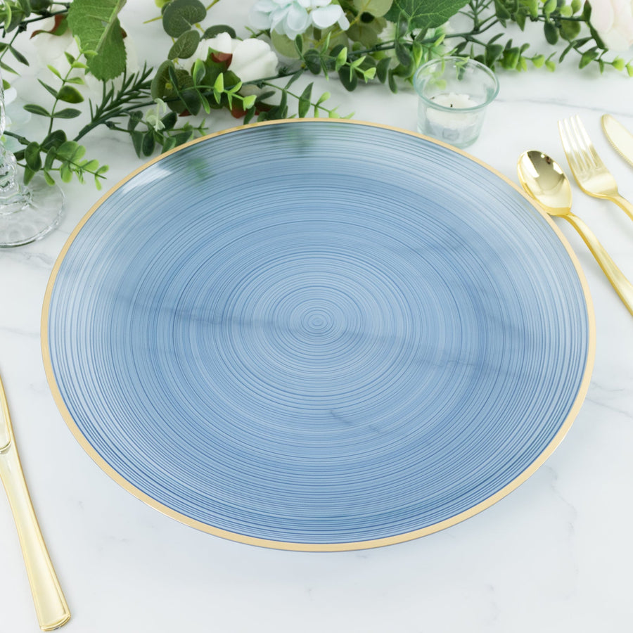 Blue decorative plate with gold trim surrounded by greenery and tableware.