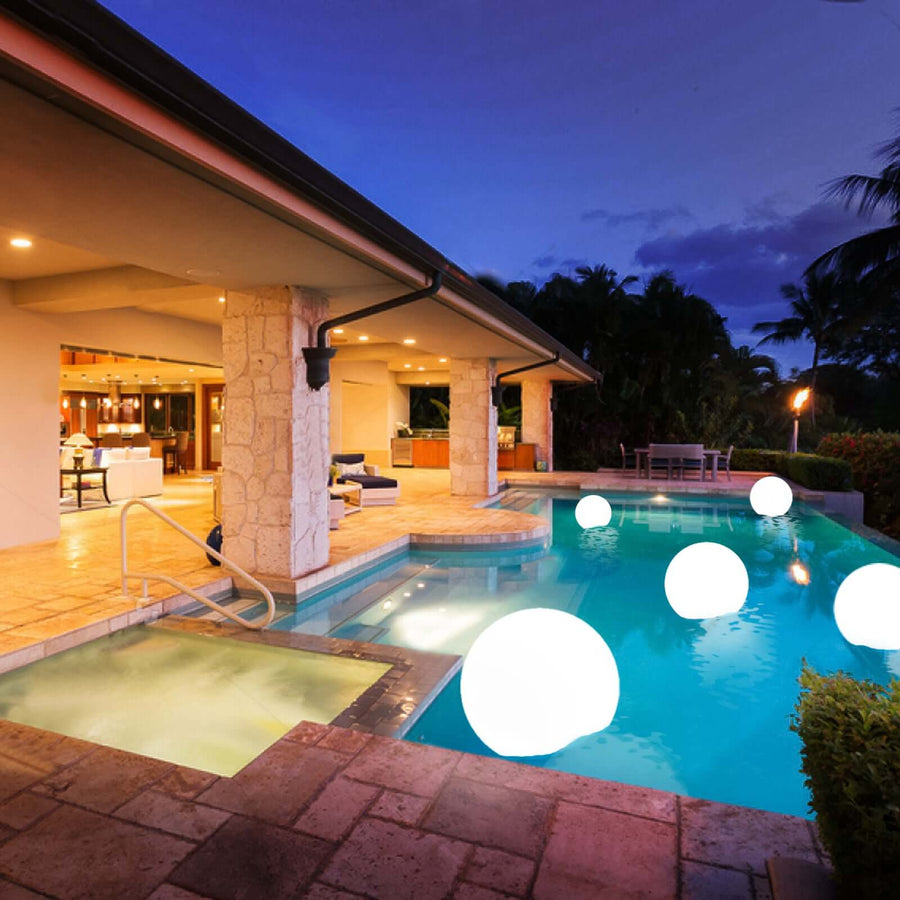 Modern outdoor pool with glowing orbs at dusk, featuring a stylish patio area.