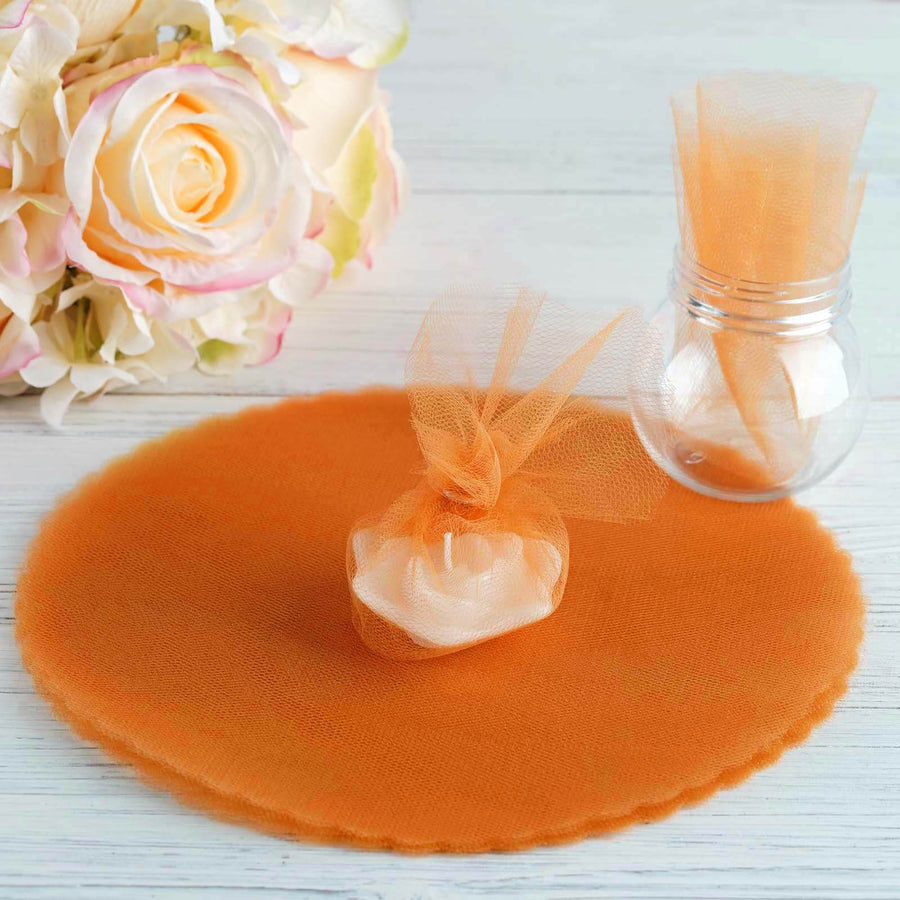 Orange tulle fabric with a small gift pouch and flowers on a wooden surface.