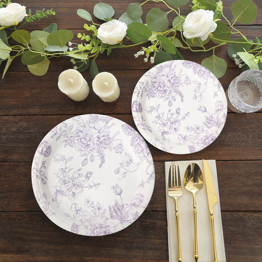 Floral patterned dinner plates with cutlery and candles on a wooden table.