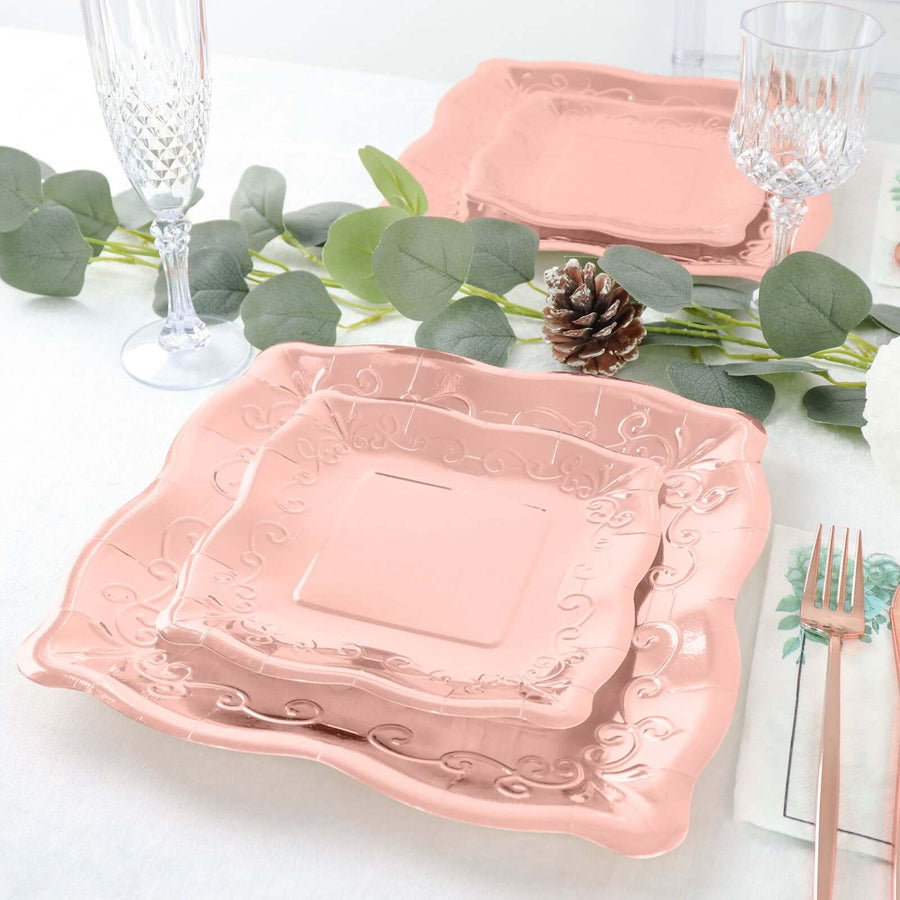 Elegant pink decorative plates on a dining table with greenery and glassware.
