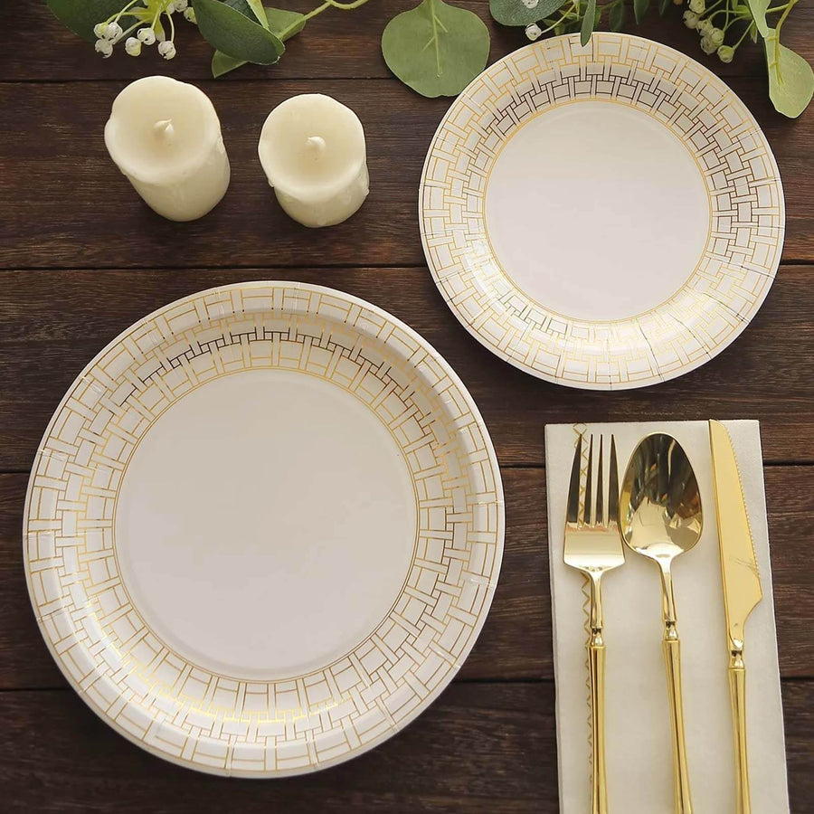 Elegant gold-accented dinner plates with cutlery and candles on a wooden table.