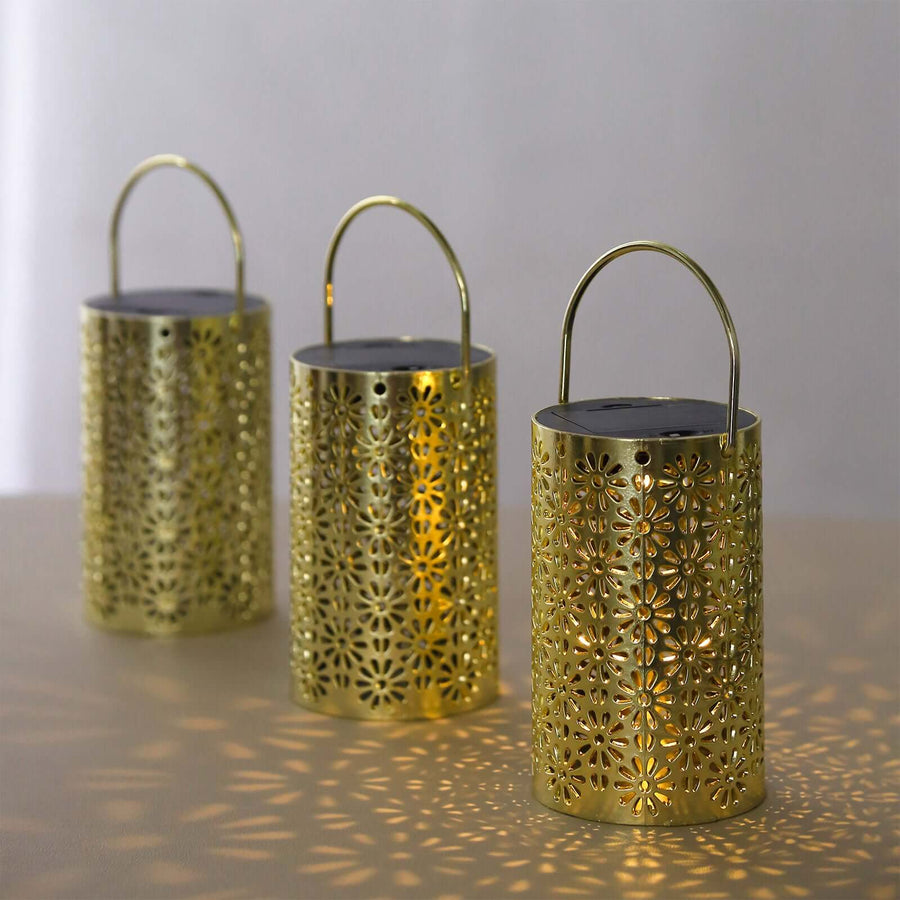 Three decorative gold lanterns casting floral patterns on a surface.