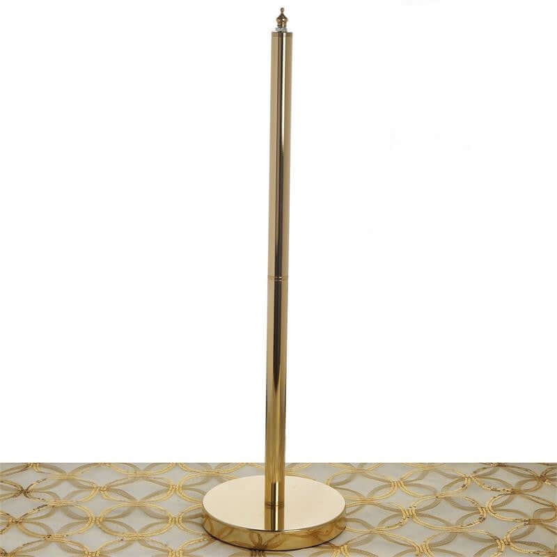 Gold jewelry display stand on a patterned surface.