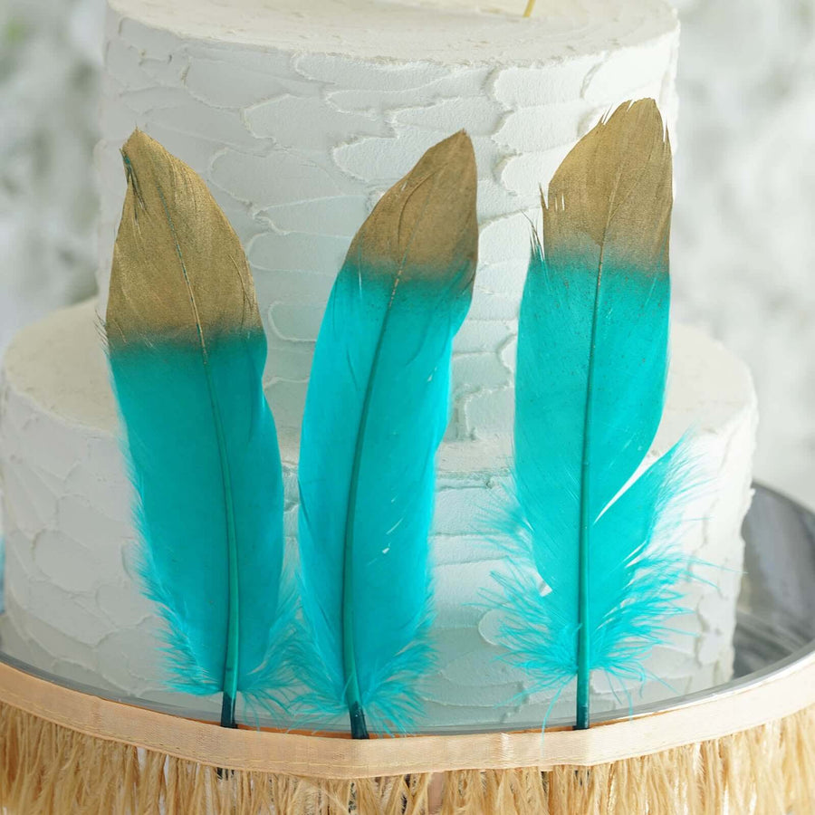 Turquoise and gold feather cake toppers on a textured white cake.