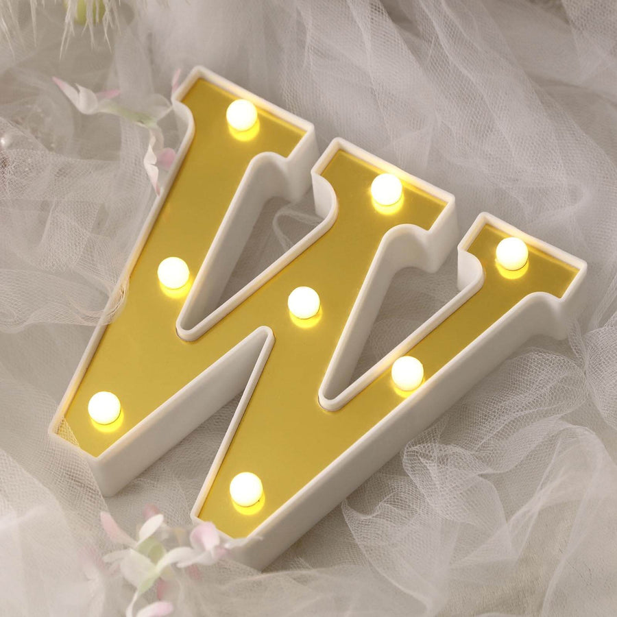 Decorative yellow letter W with lights on a soft background.