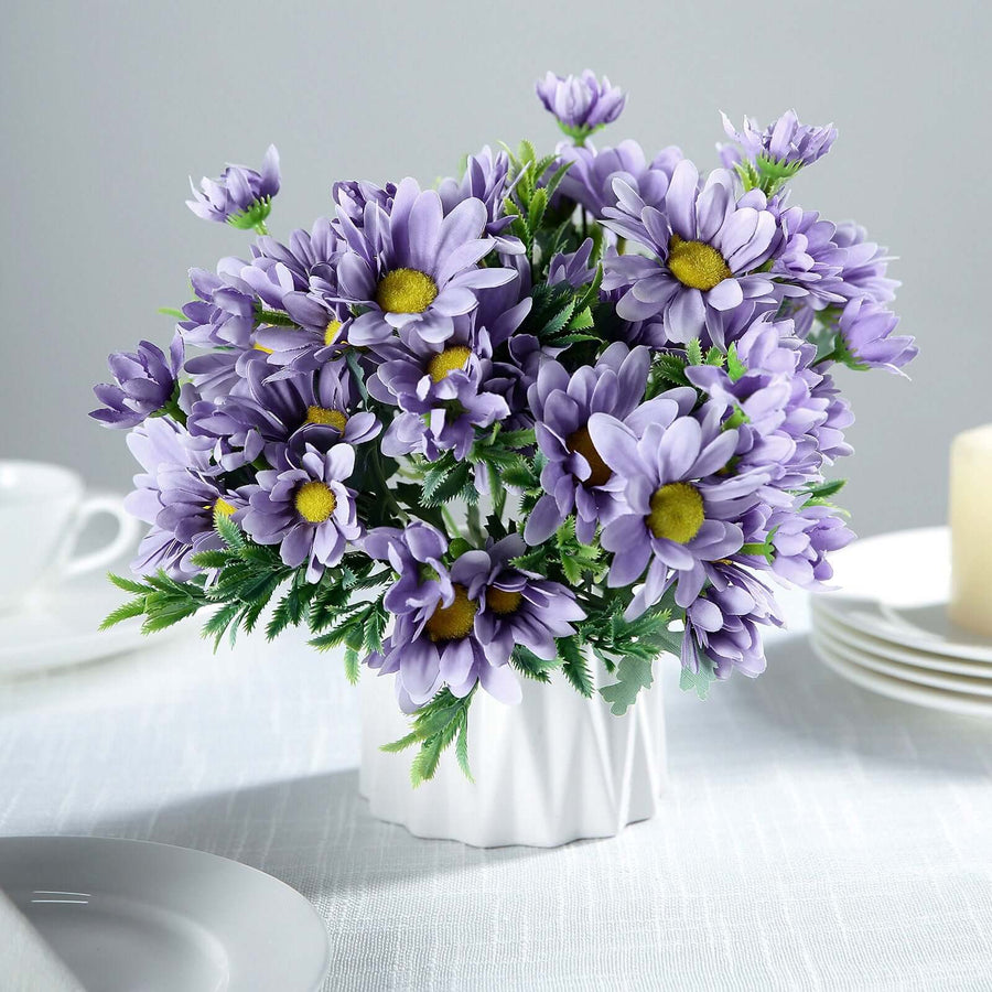 Purple daisy flower bouquet in a white vase on a table setting.