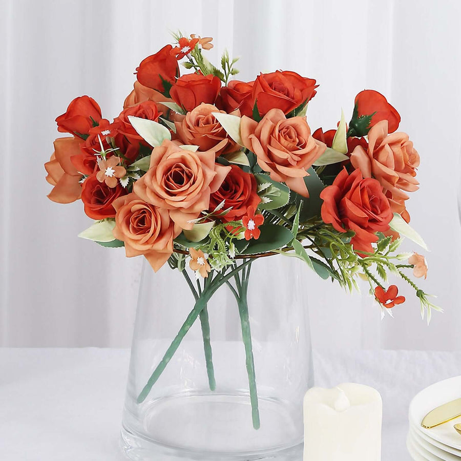 Red and peach artificial rose bouquet in a clear vase.