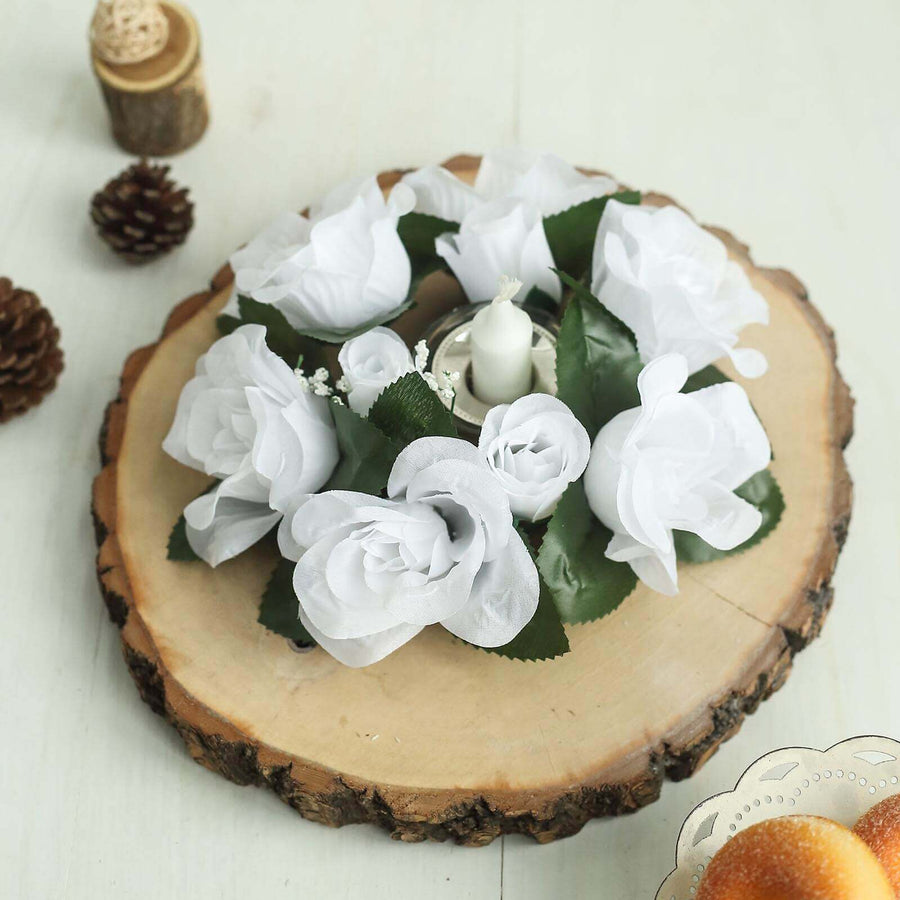White rose floral arrangement on a wooden slice with a candle centerpiece.