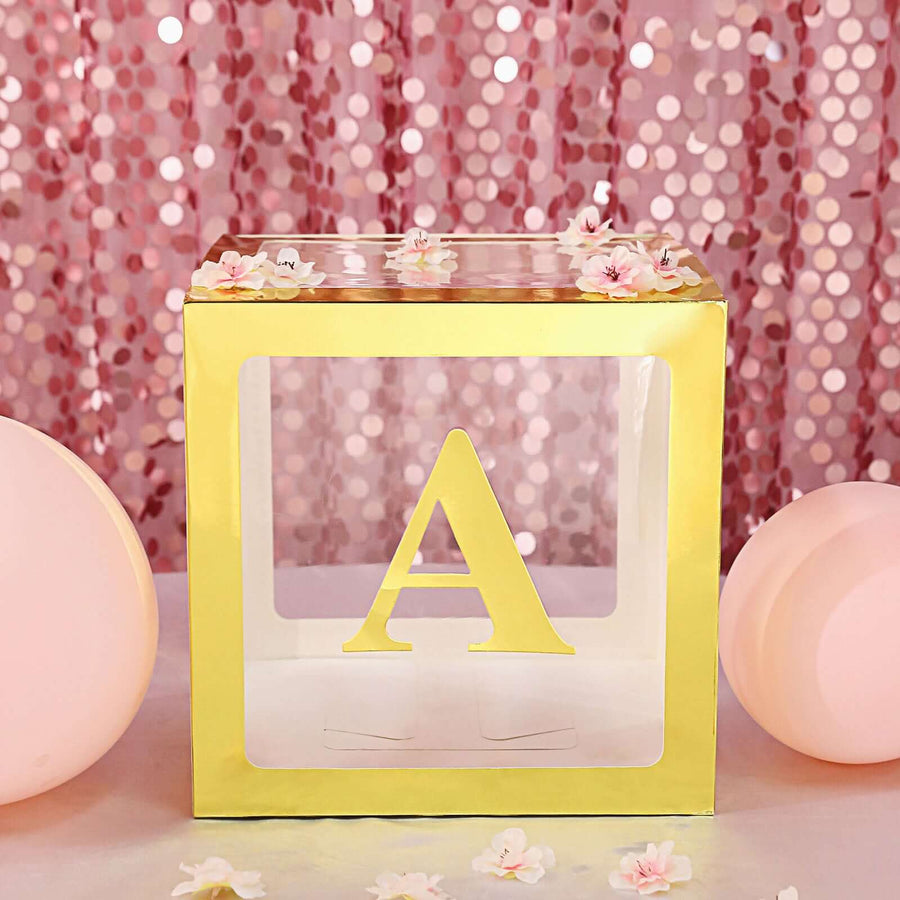 Gold and clear decorative letter A block with floral accents on a pink backdrop.