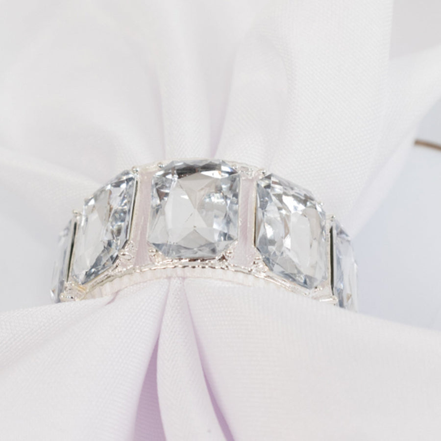 Silver ring with multiple large gemstones on a white fabric background.